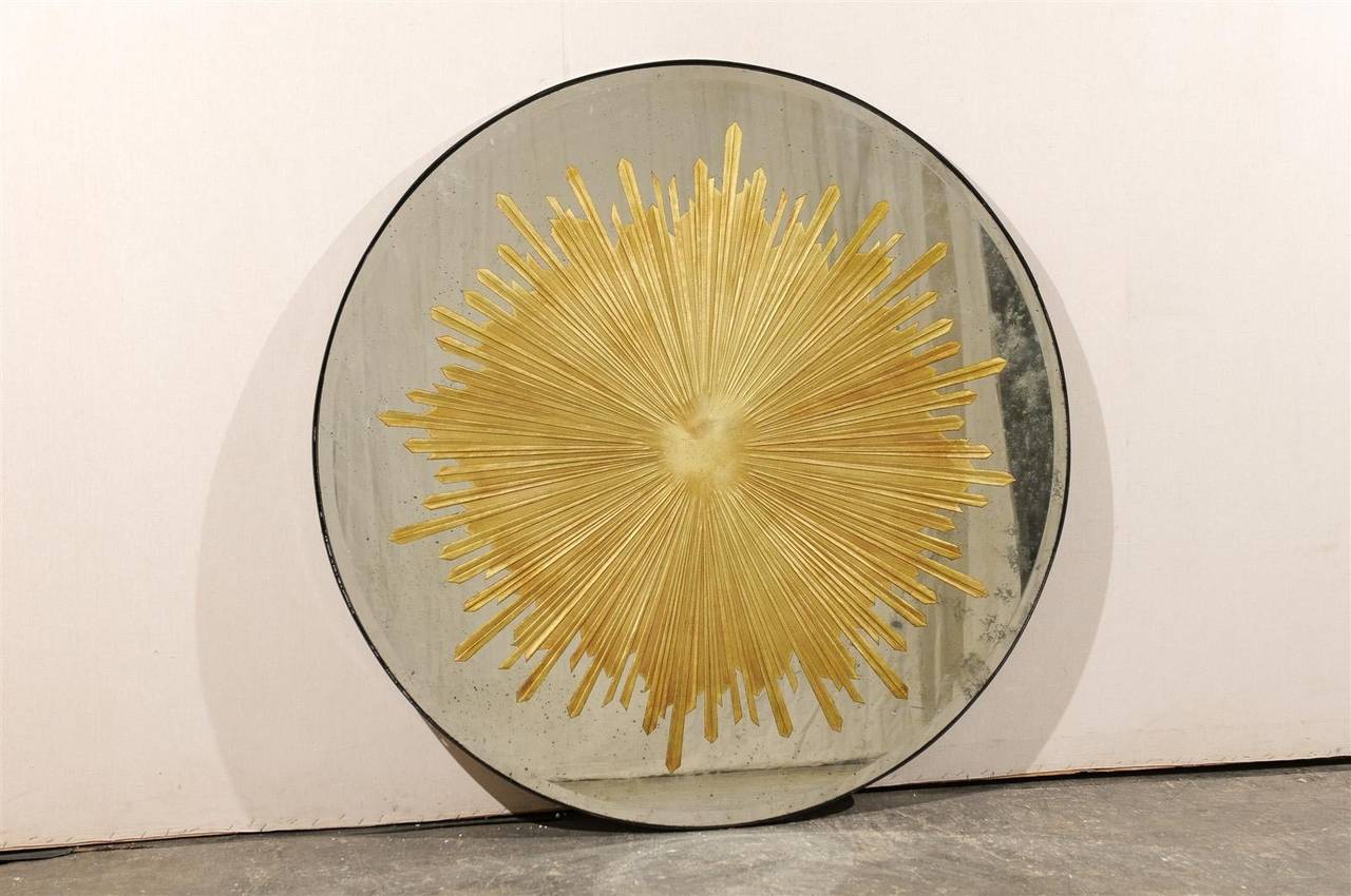 A gorgeous round shaped American antiqued mirror with central églomisé́ sunburst motif. A show stopper!