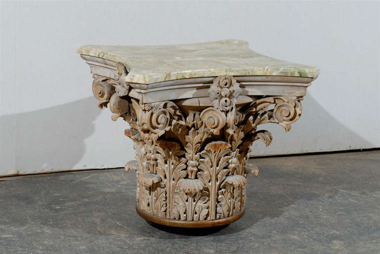 A gorgeous mid-20th century American carved wood Corinthian capital side table with the later addition of a marbleized wood top.