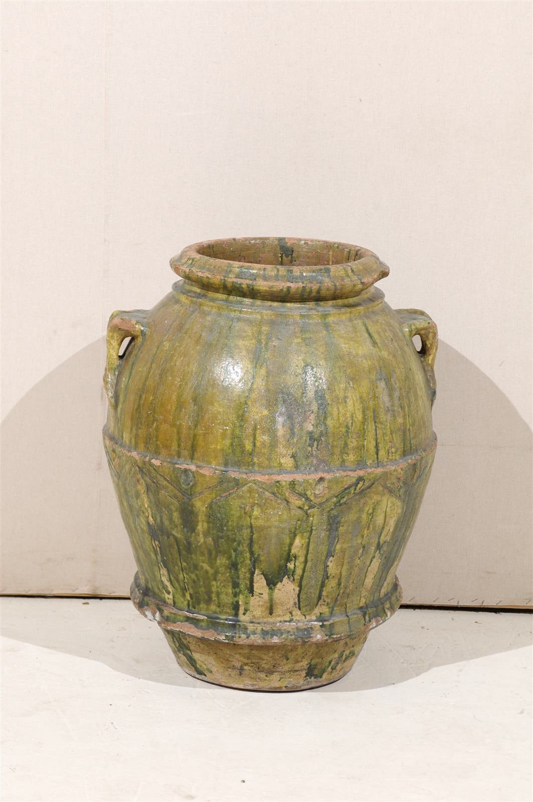 A large Italian 18th century green glazed terracotta double handled jar. This Italian jar features rich green paint of dark and light tones that have a poured effect over the jar. This large Italian jar also has some nice repeating triangular