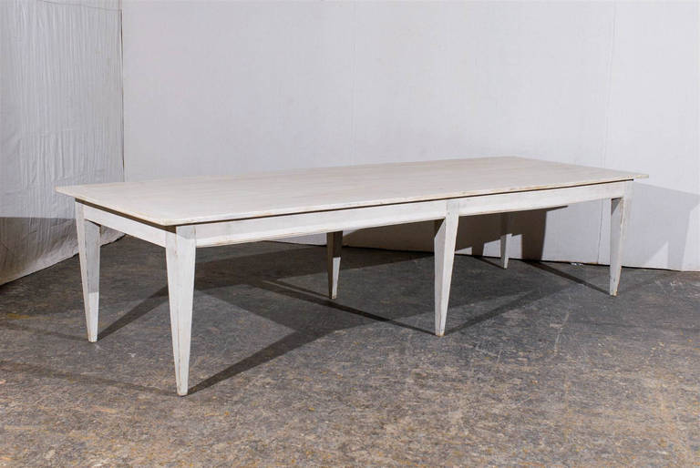 A 19th century French pine long dining table with 6 tapered legs. Pale custom finish with paint and polyurethane.