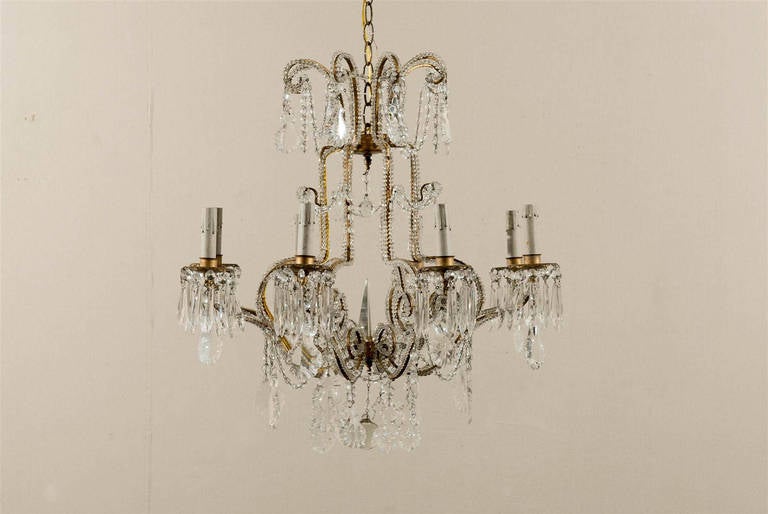 A pair of Italian crystal eight-light chandeliers. Each chandelier has a central spear and the arms are decorated with crystal beading all along. The crown part is made of eight scrolled arms, from which pendeloque crystals hang. In the lower part,