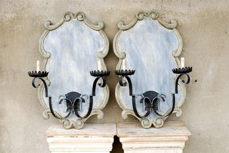 A pair of vintage French iron sconces mounted on large wooden plaques. This pair of sconces is made of vintage French scrolling black iron arms from the mid-20th century. These sconce arms are mounted on custom-made wooden cartouche like plaques.