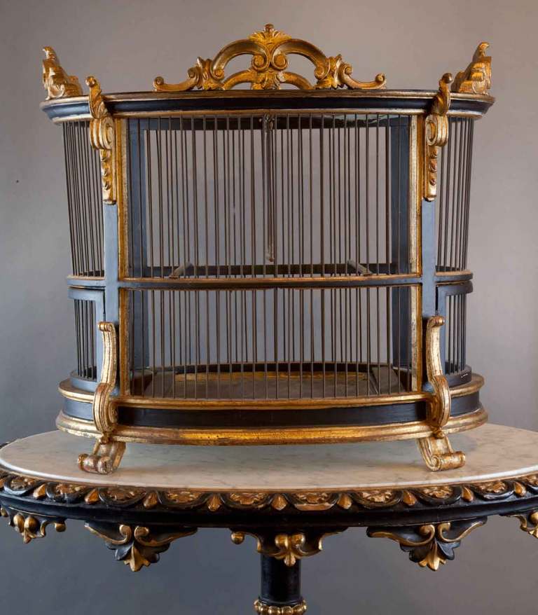 Wonderful late 19th century Italian carved gilt wood and polychrome painted birdcage, oval in form with acanthus leaf and scroll decoration, the interior with two swings, brass liner and two brass feeding trays.