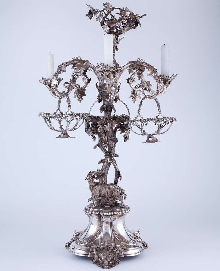 Exceptional 19th Century Silvered Bronze English Epergne by Thomas Bradbury & Sons, Sheffield England 1853-1857. Decorated with goats, grapevines, three hanging baskets and three candleholders topped with a basket for flowers.
