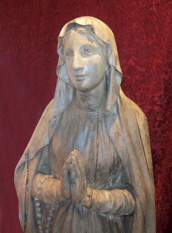 Exceptional life size French carved wooden sculpture of Our Lady of Lourdes, hands clasped in a prayerful attitude, with beautifully carved rosary and cross trailing down from her right arm.  Traces of old paint remain, mounted on a later