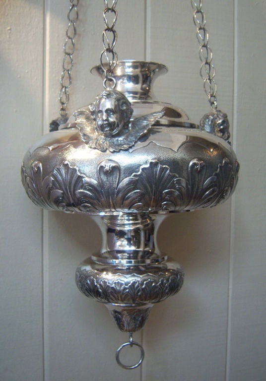Sensational Continental silver hanging sanctuary lamp by Jean Van Damme of Bruges, Belgium, of bulbous form with acanthus leaf repousse decoration all around and three applied winged angel head supports suspending chains attached to a crown form