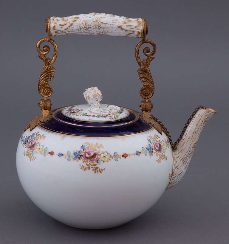 A fine and rare Meissen porcelain teapot, of melon form with cobalt blue border, painted and gilded florals, the lid decorated with a molded rose bud finial, the handle and spout in the form of gilded branches. Handle raised by bronze Doré-stylized