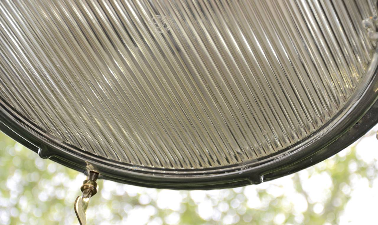 Brillianty polished light fixture by Crouse Hinds. This vintage WWII era searchlight has been fitted with iron chain to hang from ceiling. Excellent original ribbed glass lens and brass fittings. Retrofitted for standard bulbs.
Height from top of