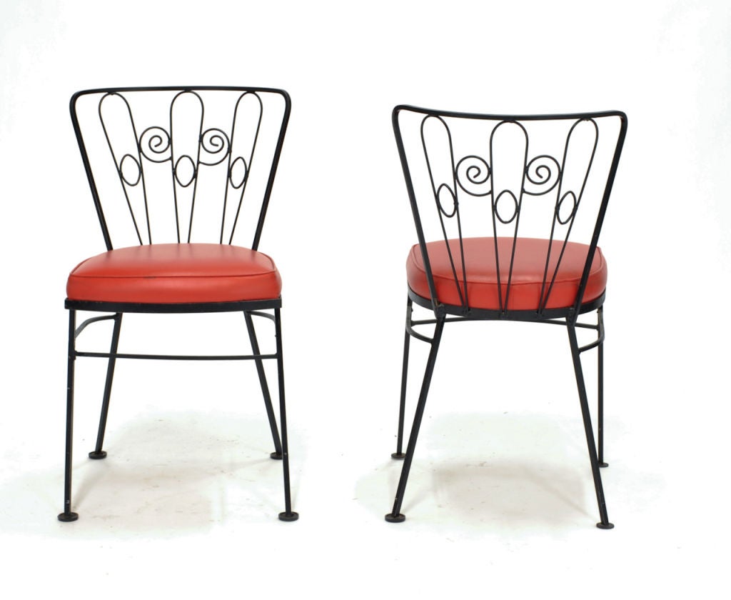 Set of 4 whimsical metal frame and  upholstered dining chairs. Constructed of iron, and upholstered in original red faux leather.
