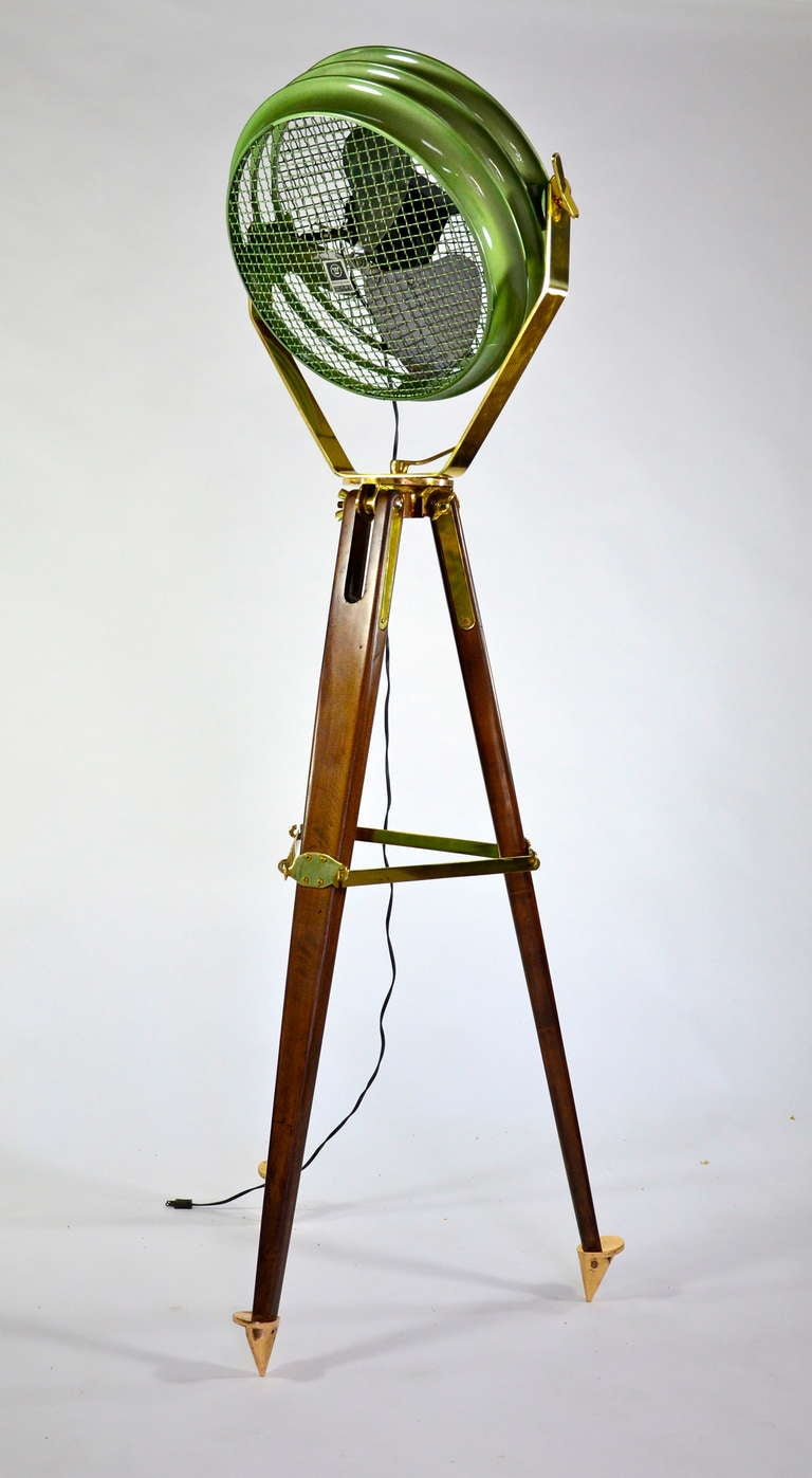 Tall, dark, and handsome, this industrial fan is mounted to an oak US Navy tripod. The fan has 2 speeds and has been finished with an industrial green enamel. The well built tripod is refinished and features its original brass fittings. Fan is 20