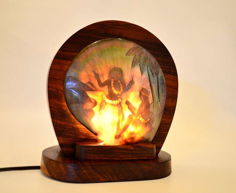 Polynesian tv lamp comprised of carved shell depicting carefree  hula girls against a tropical back drop.