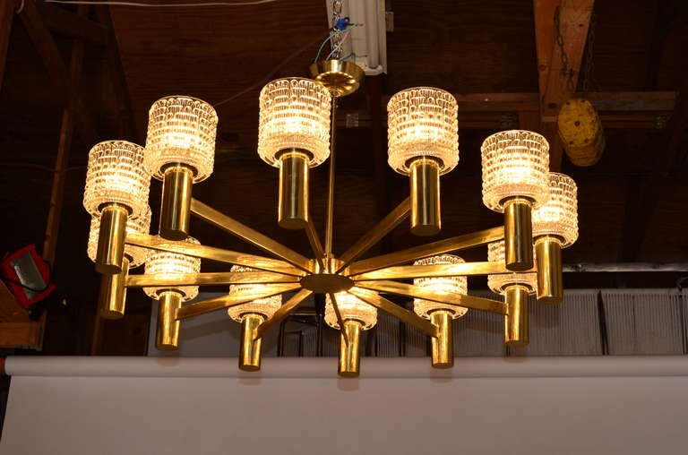 Large scale brass Chandelier by Prescolite. Lamp is quality made with solid brass construction and features 12 textured glass shades which softly diffuses light output. I have 2 available. These would make excellent ball room fixtures.