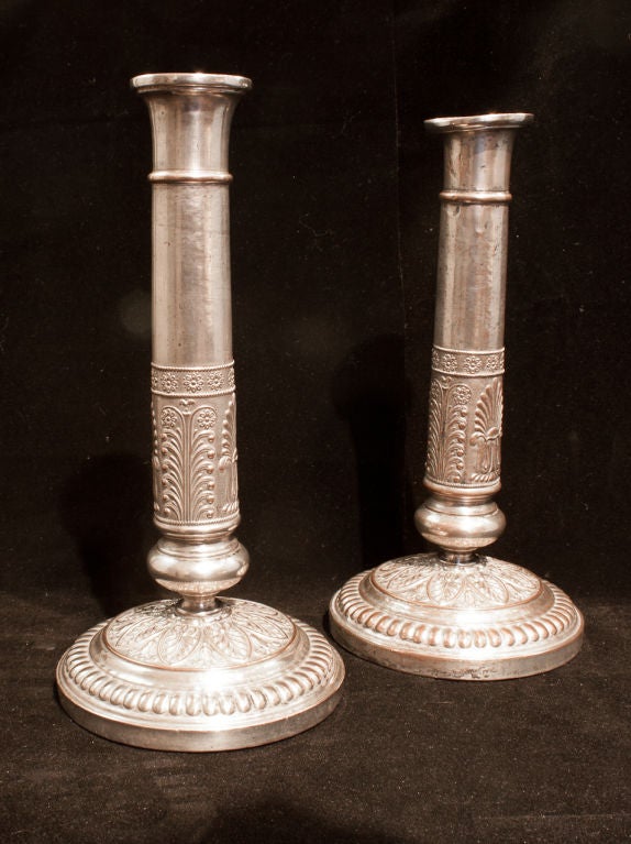 Pair of silver plate French Empire candlesticks. With embossed decoration to the base and the column. The silver plating is lightly worn.