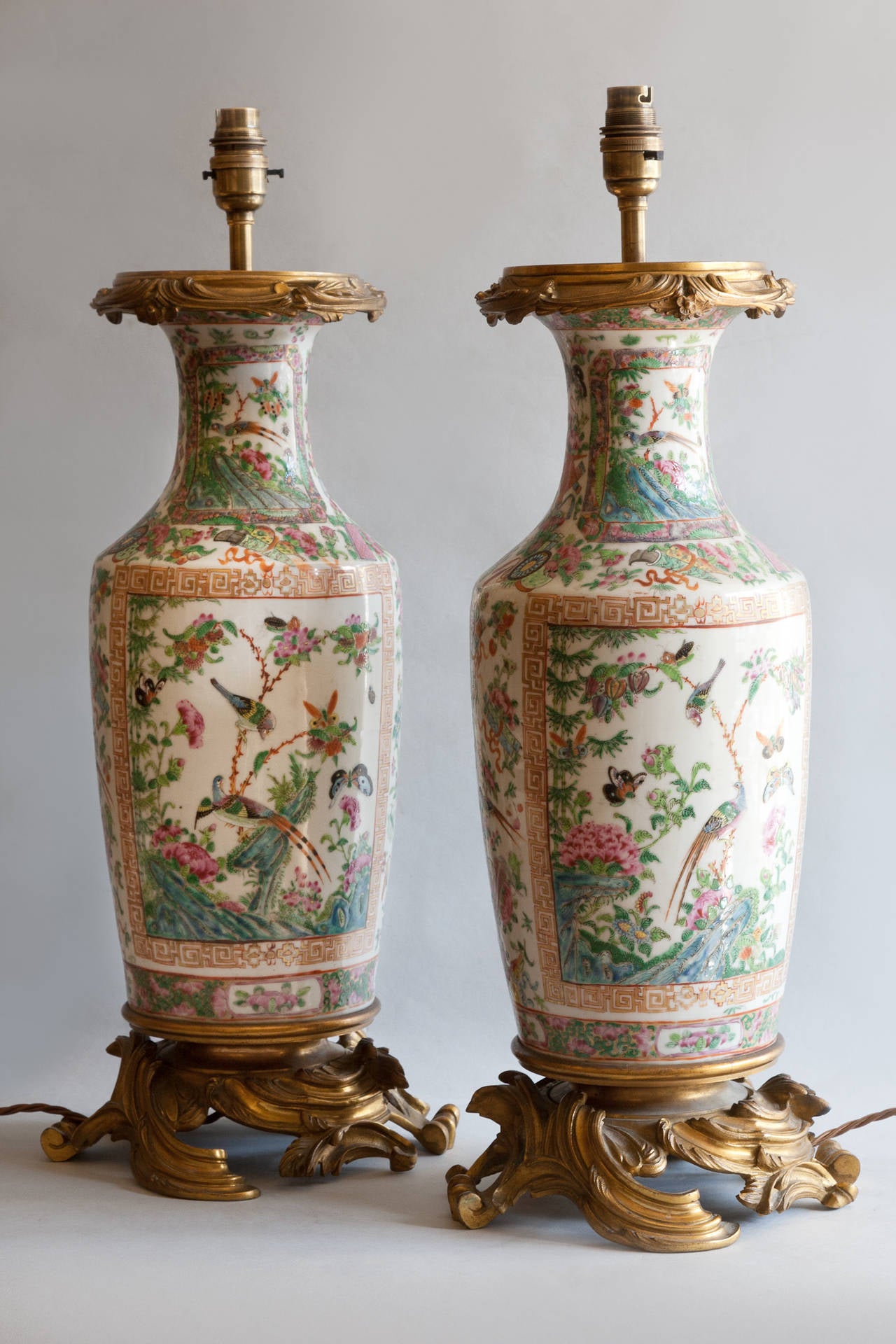 The vases of rouleau form with 'famille rose' decoration of birds and flowers in shades of greens and pinks on a white ground. With finely incised gilt bronze mounts. 

Shown with 22
