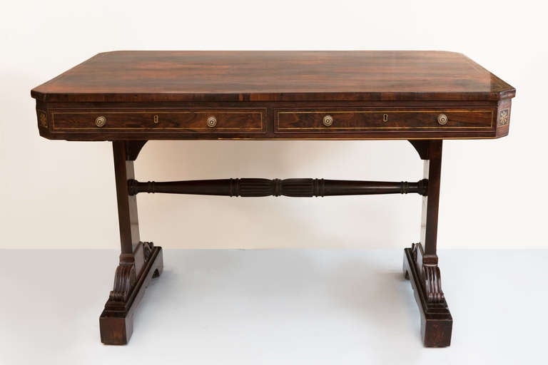 Two short drawers and one long drawer with a dummy on the opposite facing side. Joined by a turned stretcher and supported on scroll mounted feet with original brass castors. Rosewood with brass inlay. In the manner of George Bullock.
Please note we