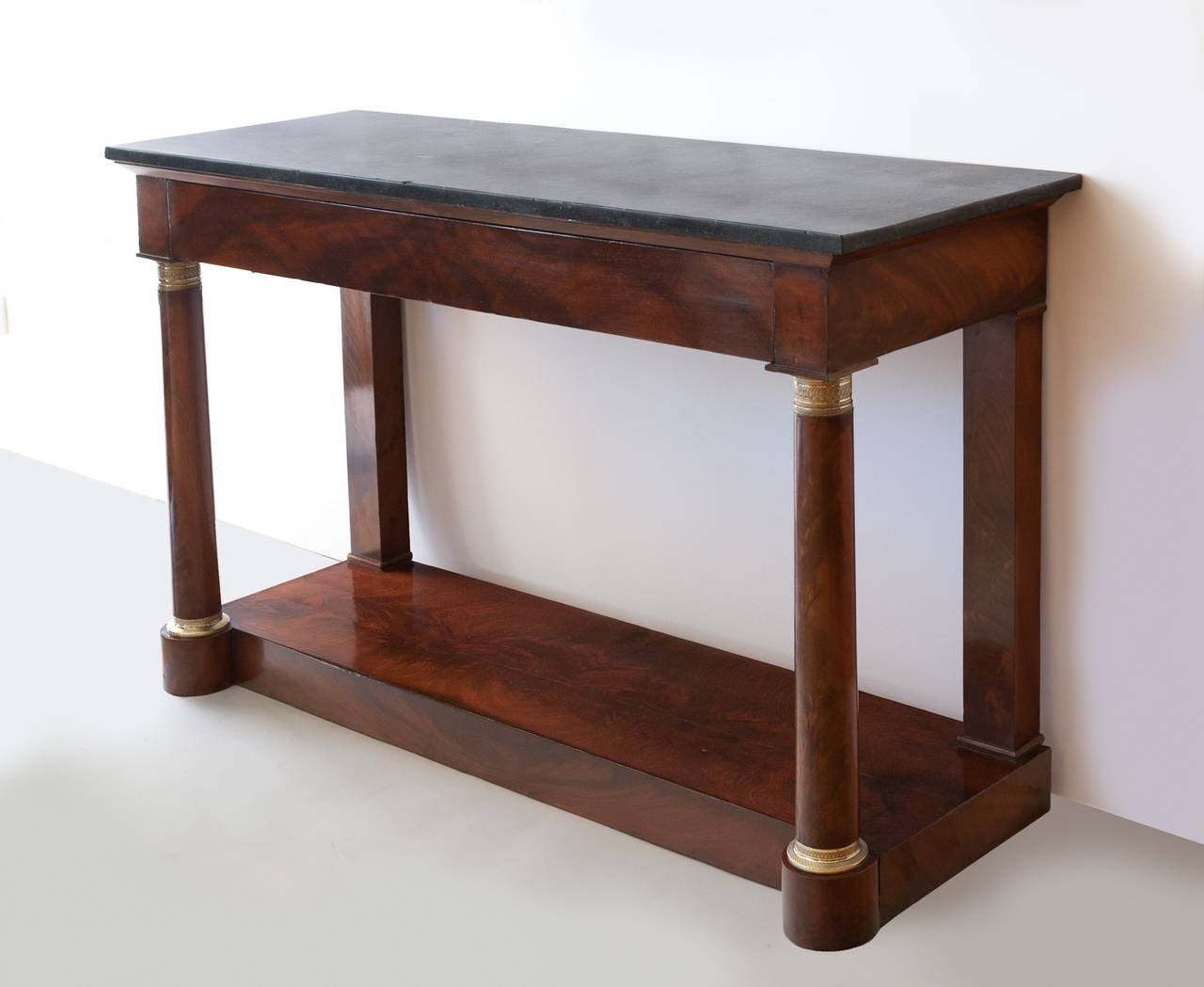 Mahogany and mahogany veneer. Black fossil marble top over one long drawer. Gilt bronze mounts. France c. 1810. Some slight lifting on the veneer, see photographs.