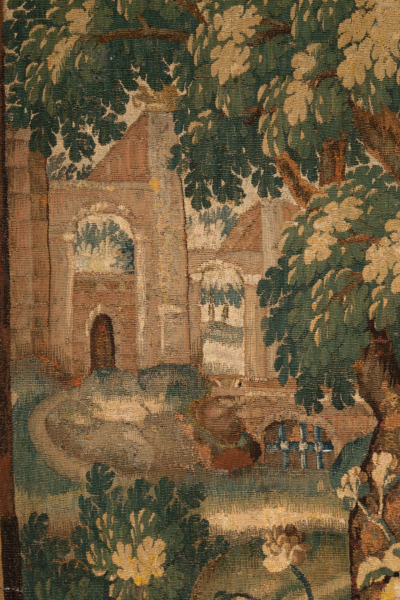 With trees and foliage in the foreground and a castle in the background. Surrounded by a border with flowers.
Woven in wool and silk. Presently un-backed. Some old restorations, see photographs for details.