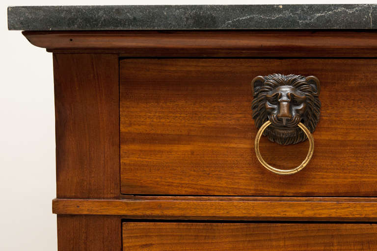 Three long drawers with ebonised carved paw feet and turned feet at the back. 
Patinated bronze lion head and ring handles, with replacement black fossilised marble top. 

This commode is a close pair to another we have stock, our reference