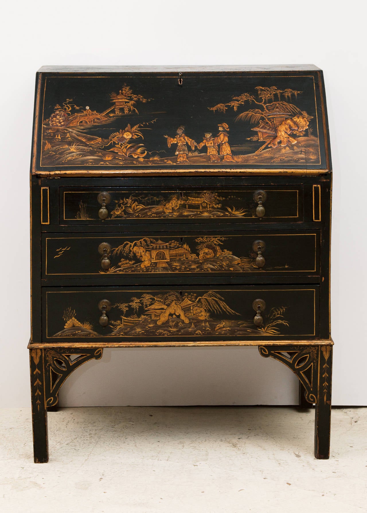 Black lacquer with gold and yellow coloured decoration in slight relief of Chinese landscapes and people. 
Three long drawers with original brass drop handles, supported on four bracket feet.
England, c.1860.
