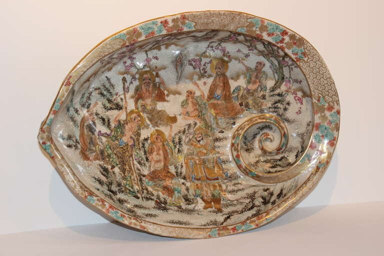 Awabi Shell-Form Satsuma Pottery Bowl, 19th Century with decoration of nine Lohans in a wisteria landscape.  Shell-Form feet and relief decoration on exterior.  Little wear to gilding.