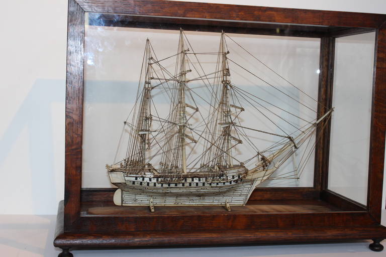 Early 19th Century Napoleonic Prisoner of War Bone Ship Model with nicely detailed rigging, intricately deep carvings on a wood base in a custom glass paneled showcase. The glass case is 9 1/2
