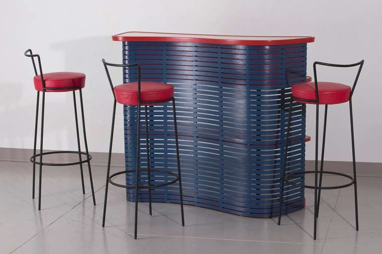 Bar in painted slatted wood with formica top and and three barstools with upholstered cushions and wrought iron frames. Designed by Joaquim Tenreiro, Brazil, early 1950s.