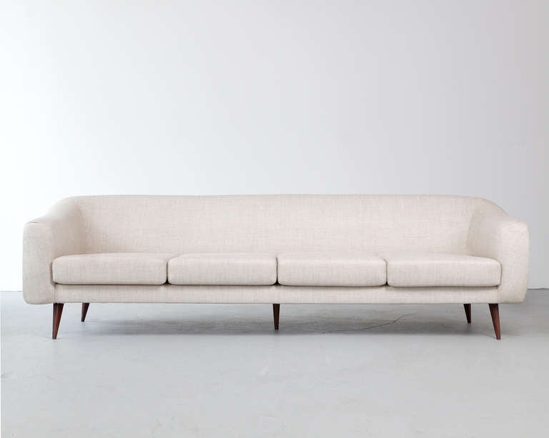 Four-seat sofa with off-white upholstery and jacaranda legs. Designed by Joaquim Tenreiro, Brazil. (Seat measures: 15