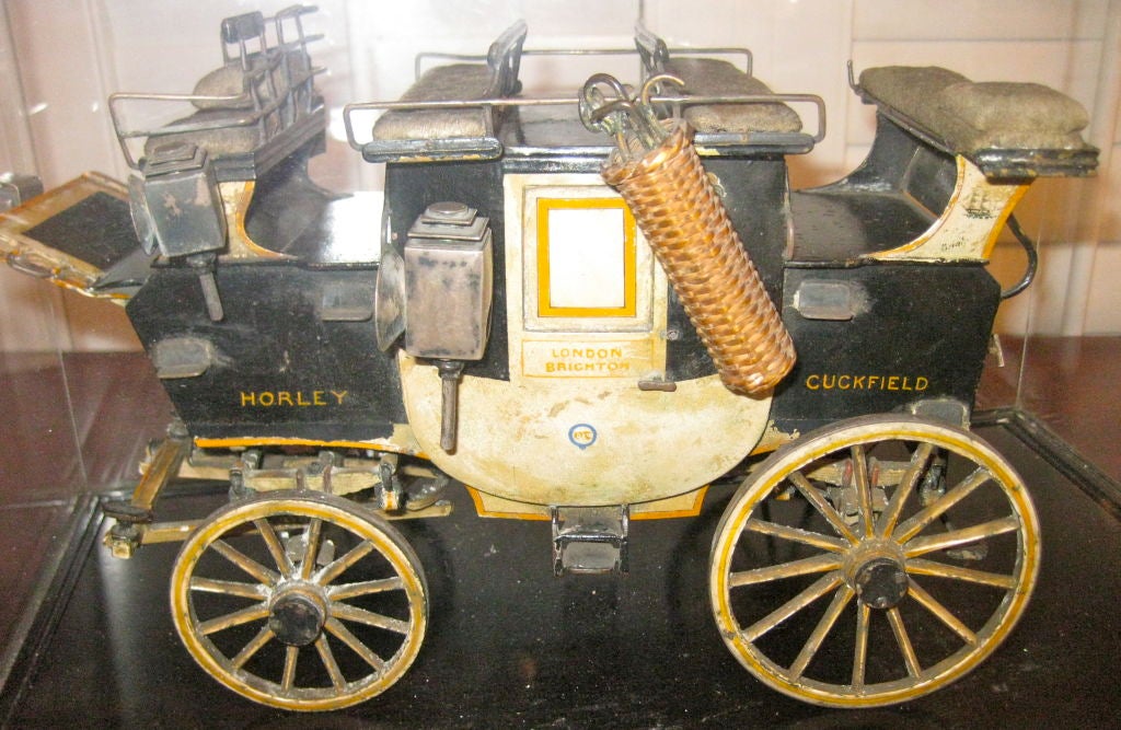 English 19th Century Tole Miniature Carriage <br />
on black wooden platform under a glass case<br />
Signed: London, Horley Cuckfield