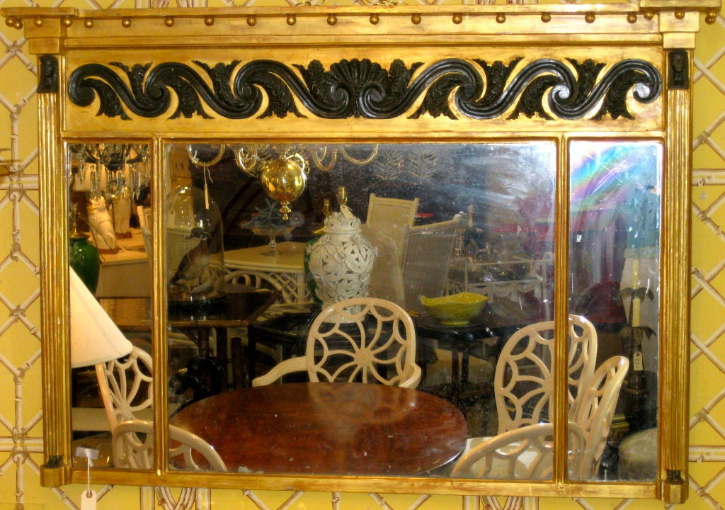 English 18th century Regency period overmantel mirror with water gilt in the classical style having ebonized raised carving a of shell, along with scrolls and leaves, with Egyptian figure heads and feet on each side.