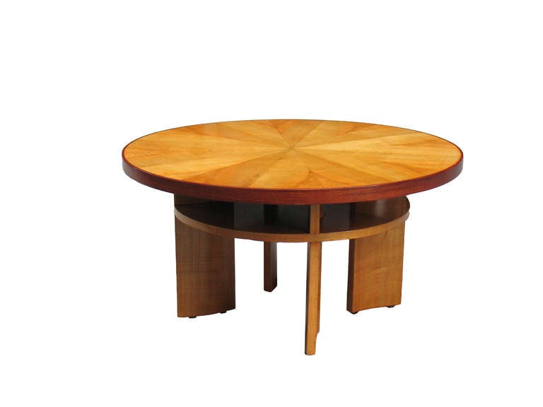 This French Art Deco sofa table with a large diameter features an unusual design with a useful plateau under the tabletop. 
Four shaped supports and an unusual coloration and grain by using a rare light tiger maple veneer. 
Tabletop sunburst