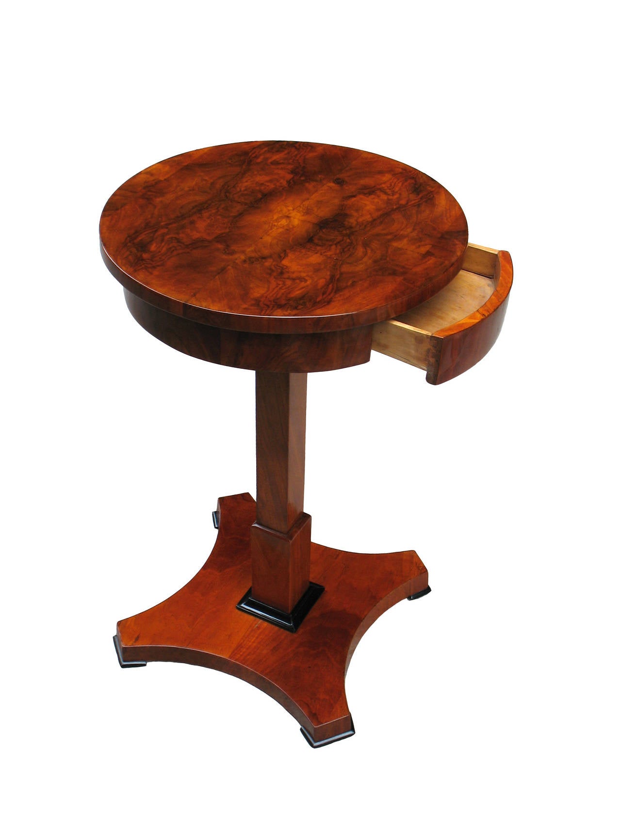 This South German Biedermeier side table is veneered with walnut on pine, book match on table-top. One drawer apron raised on a square pedestal over plinth on a four times concave shaped base. Ebonized trim.

References are included in our