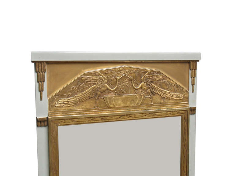 Neoclassical inspired French Art Deco gilt-wood wall-mirror. Bordered with the original grey painted frame. Wood carved gilt-wood mirror-frame topped with a gilt-wood panel with an unequaled detailed plaster relief-motif of 2 swans. Original