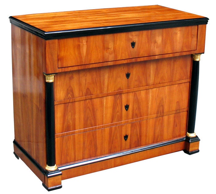 This four-drawer Biedermeier chest can be converted into a writing desk. Cherry wood on pine in book match pattern. Front flanked with ebonized half columns. Gold leaf trim. Fitted interior. Original locks and hinges.

References are included in