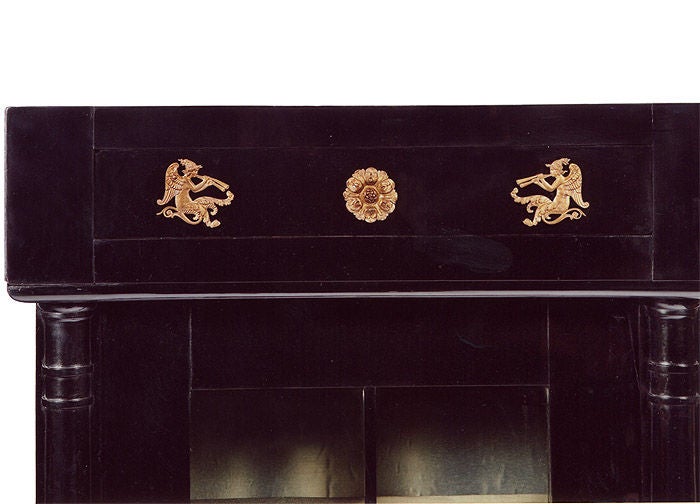 A rare pair of architecturally designed ebonized Biedermeier vitrines. Paneled and glazed doors flanked by half columns between socle (with hidden drawer) and cornice, "architrave" (with fake drawer). Original bronze ormolu mounts (winged