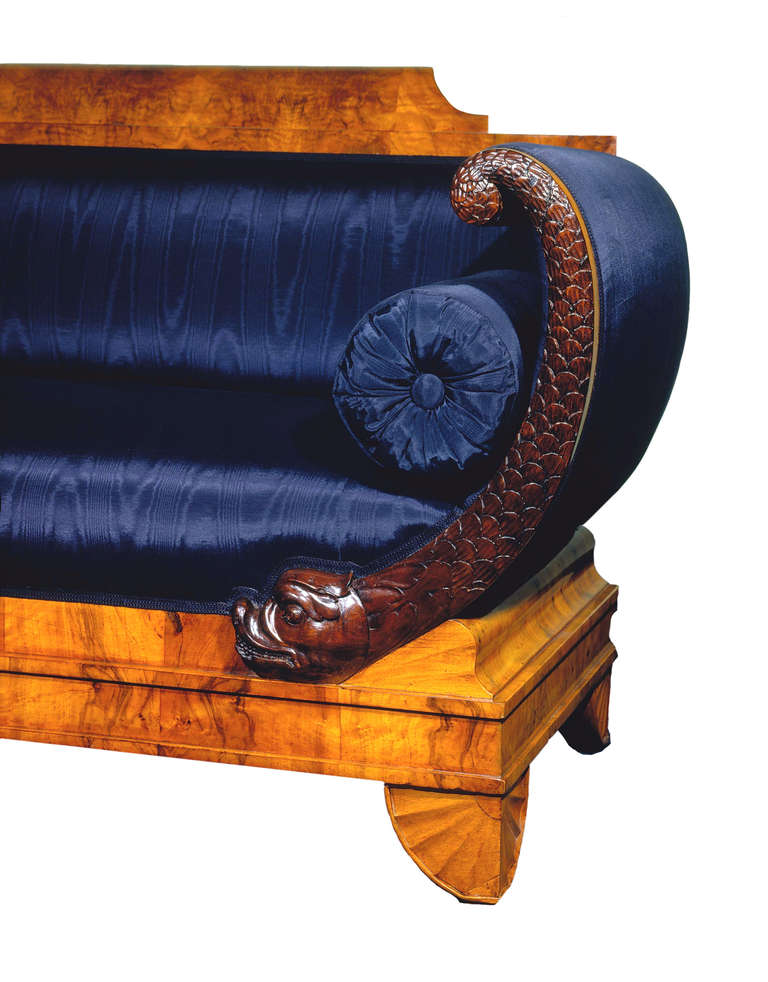 This unique, documented North German Biedermeier sofa (region of Rhineland) is matching veneered with walnut on pine. Sides with high relief wood-carved dolphins which are "resting" on rare folded cushions. Stepped rail on outstanding