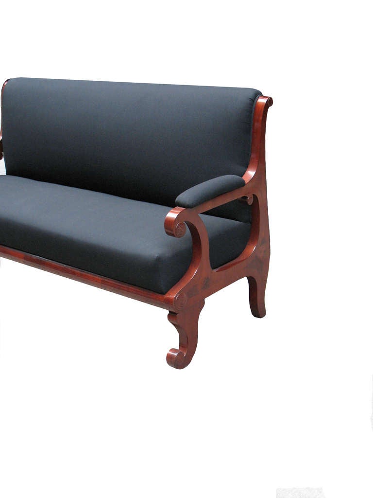 A side-frame constructed and upholstered Biedermeier bench or sofa. Mahogany veneered on pine wood with three diamond-shaped inlaid panels and five wood carved discs. 
Very comfortable with a deep drop-in seat and tall out curved seat back. Padded