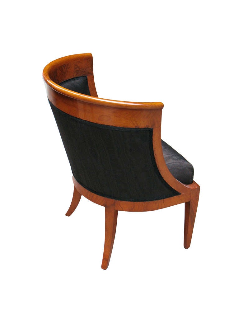 This comfortable Biedermeier barrel-back bergere is veneered with Caucasian walnut on oak. Book match veneered shoulder board. Padded seat back. The elegance of this design is given by the shallowness of the bergere, the down swept side frames, the