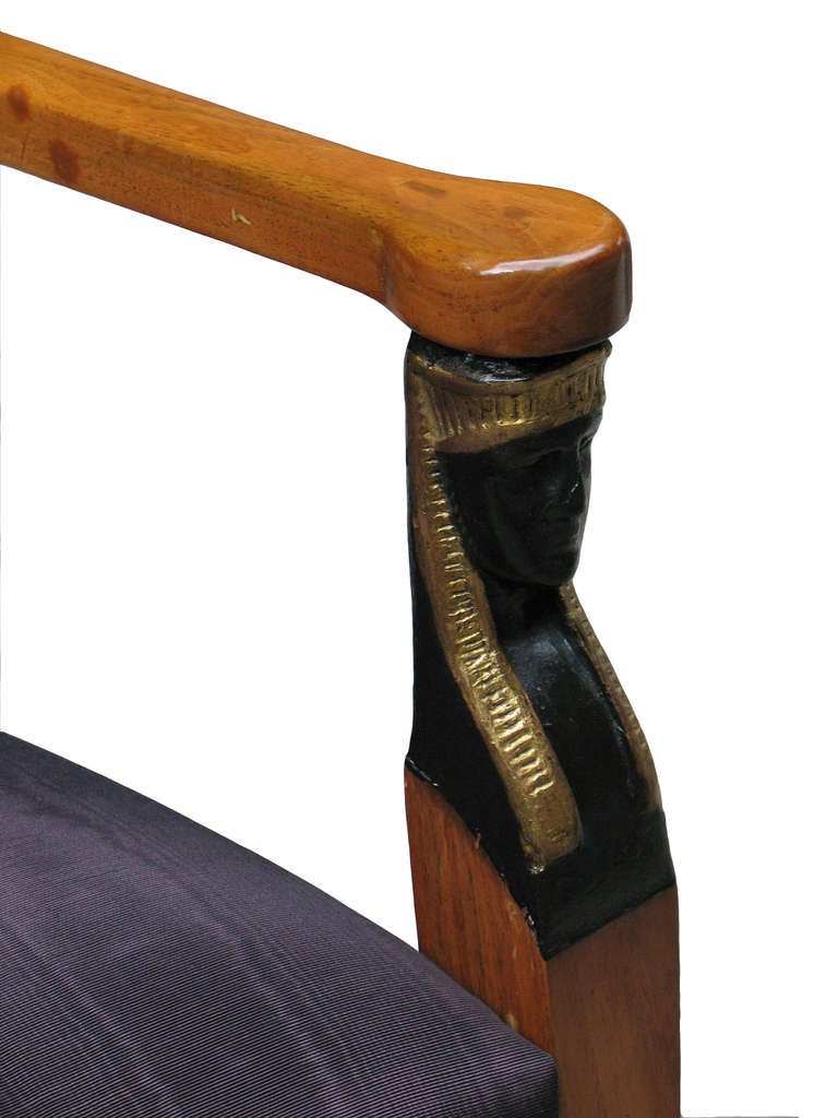 This South German armchair with a typical Biedermeier design (straight rail, arms, square-tapered legs, rectangular out-bent padded seat-back), featuring ebonized and parcel-gilt Egyptian uprights to support the arms, verifies the Classical