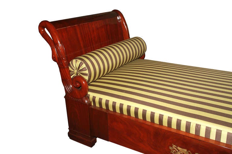 This French Directoire-inspired Biedermeier daybed is large and comfortable, veneered with mahogany on pine, and decorated with sculptured, looped swans with fine woodcarvings, ending in powerful scrolls above pedestals. Rails on 3 sides with