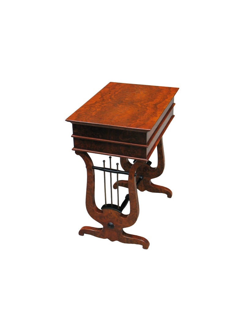 This table's importance is the dominance of one of the Biedermeier main motifs, the lyre, which supports the 2 drawer table-top. Walnut root veneer and burl in book-match pattern on pine wood. Drawers in solid maple. Ebonized trim turned stretchers.