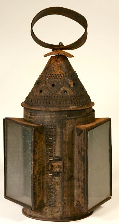 A beautiful hand-held three-pane lantern decorated in an intricate pierced pattern (see detail shots). Made of heavy-gauge tin, this piece may date to the 18th century. Height measurement below includes the handle; the body of the piece, to the top