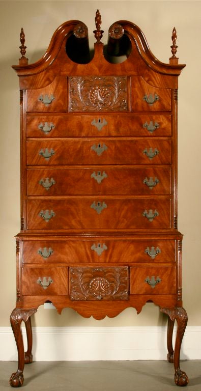 This beautiful 2-piece bonnet-top high chest features: carved rosettes; urn-and-flame finials; 11 drawers of various sizes, two of which are beautifully carved with shell and floral motif; both upper and lower drawer sections are flanked by fluted