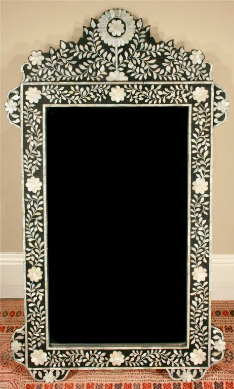 Offered is a beautiful, large-scale wall mirror whose entire ebonized frame is decorated in an intricate floral pattern composed of hand-cut pieces of mother of pearl. Fitted with heavy-duty hanging hardware (see detail shot). What appears to be a