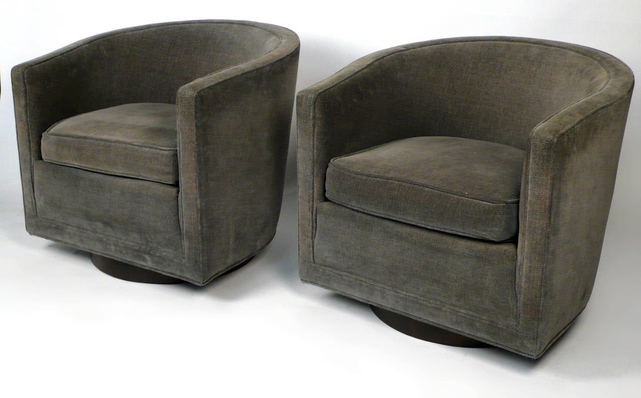 Matching pair of swivel lounge chairs designed by Edward Wormley manufactured by Dunbar. Original upholstery with round walnut base, seat height 17