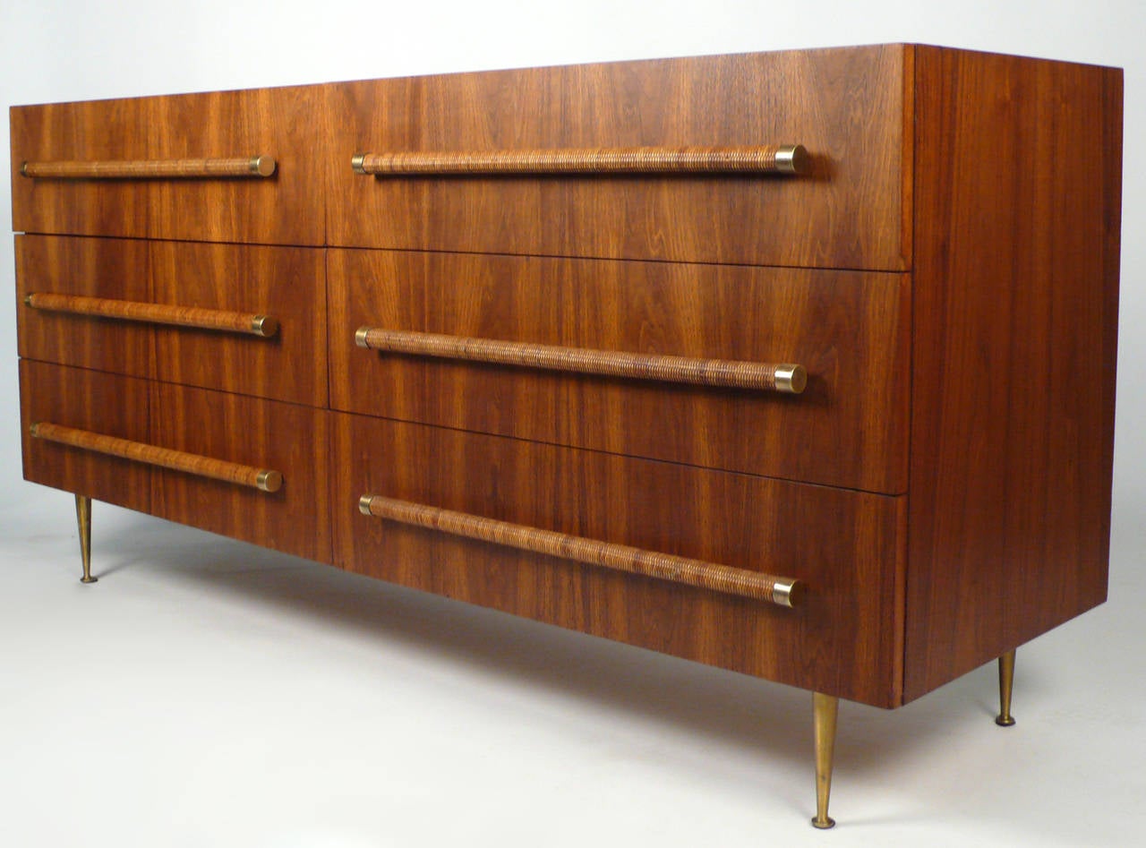 Beautiful six-drawer dresser designed by T. H. Robsjohn-Gibbings for Widdicomb Furniture Co. The dresser is constructed from a beautiful bookmatched walnut with cane drawer and brass drawer pulls and sits on solid brass legs.