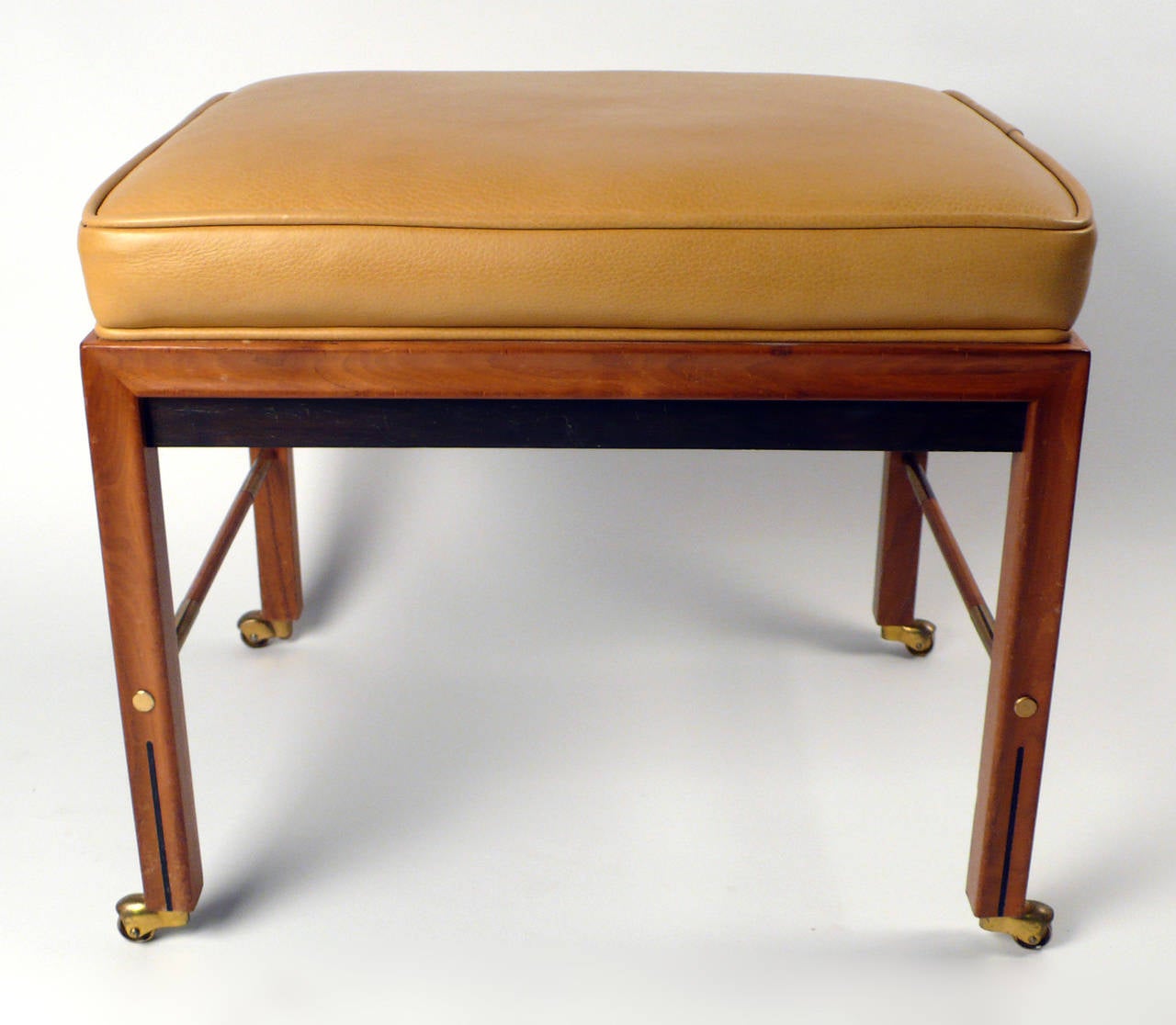 Leather stool with brass castors and inset detailing.
