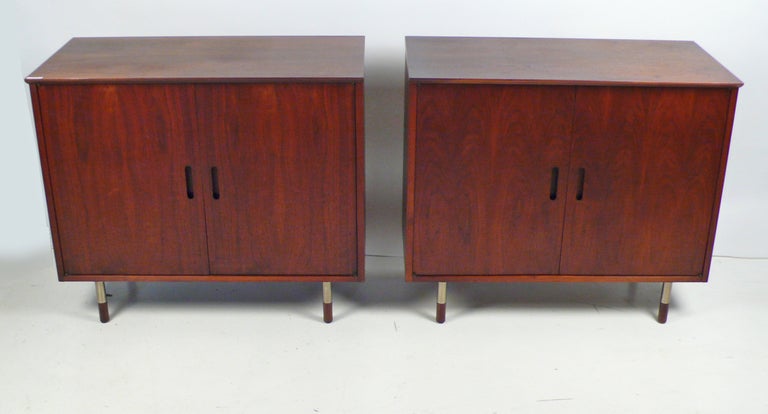 Matching pair of credenzas designed by Jack Cartwright for Founders. Constructed with walnut, doors open to reveal an adjustable shelf. Price is per cabinet.