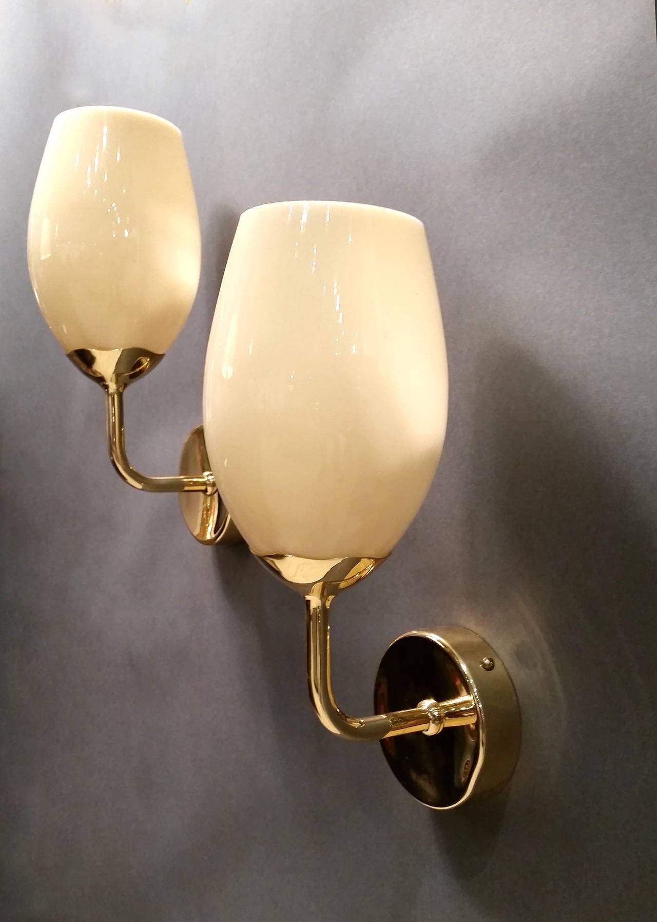 Early pair of sconces designed by Paavo Tynell for Taito Oy. Model no. 9447 stamped to mounting bracket. Opaque milk glass shades emit a pleasant colored warm light. Solid brass. Polished and re-lacquered.