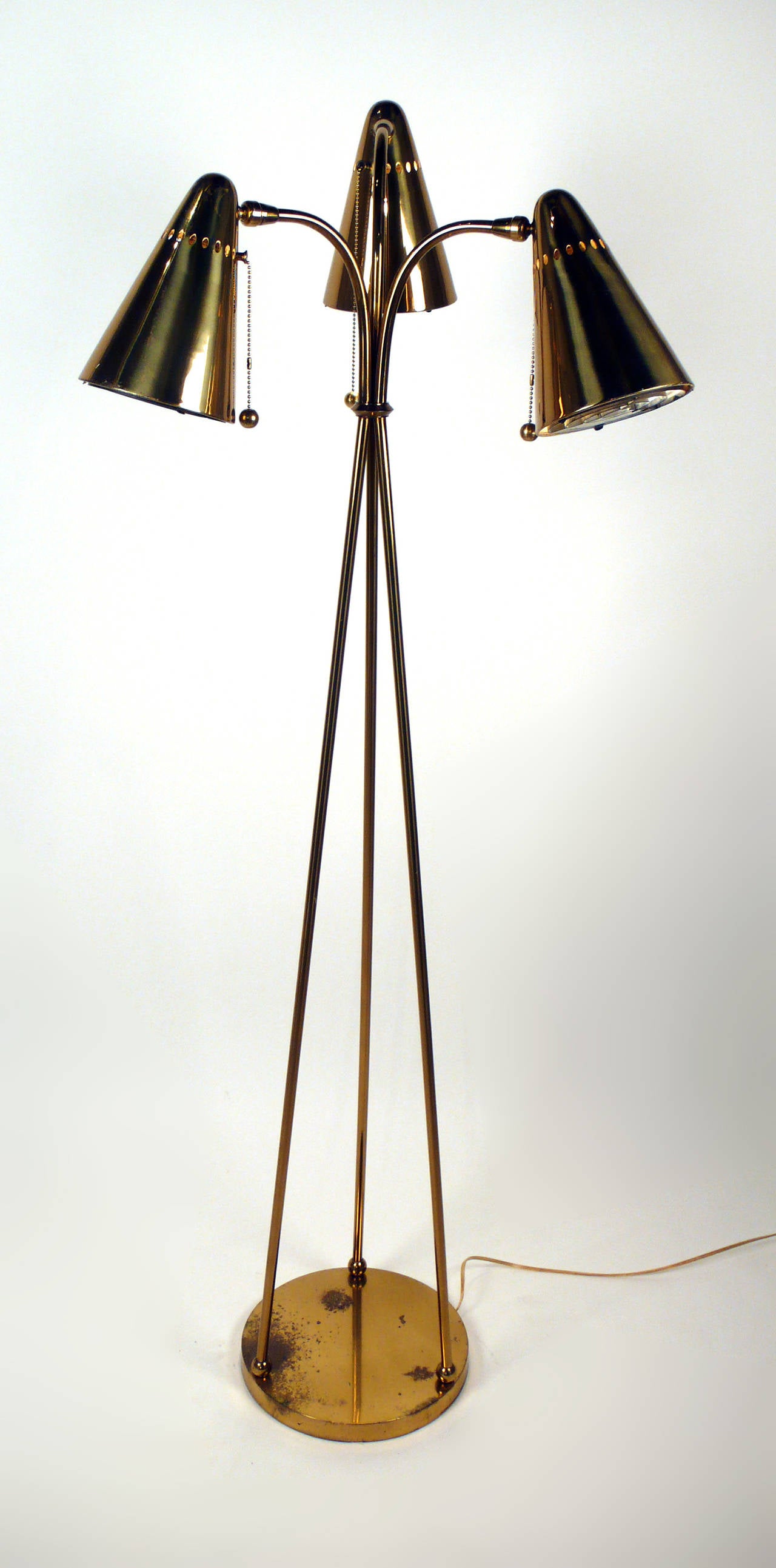 Unusual 1950s tripod floor lamp. Consists of three conical perforated brass shades with pull chain sockets and decorative brass balls. Professionally re-wired. Has similarities to lamps designed by Gerald Thurston, Ben Seibel, Gino Sarfatti and