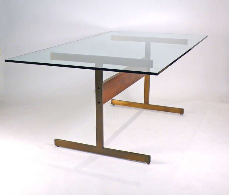 Roland Carter dining table with glass top. Would also work well as a desk. Bronze finished metal connected by a rosewood stained walnut stretcher.